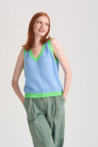 Red haired female model wearing Jumper1234 Wedgewood blue cashmere vee neck tank with contrast neon green ribs