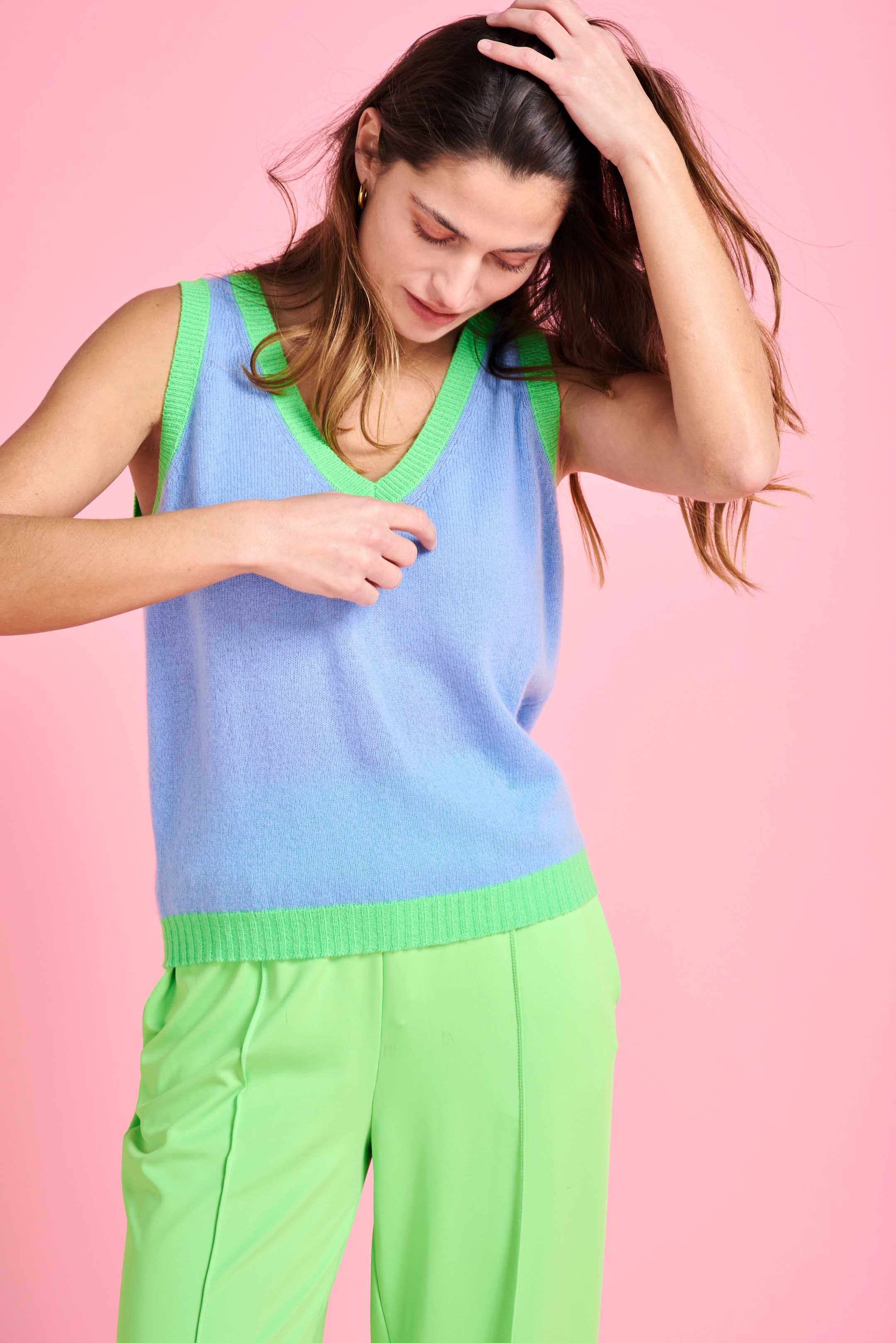 Brown haired female model wearing Jumper1234 Wedgewood blue cashmere vee neck tank with contrast neon green ribs 