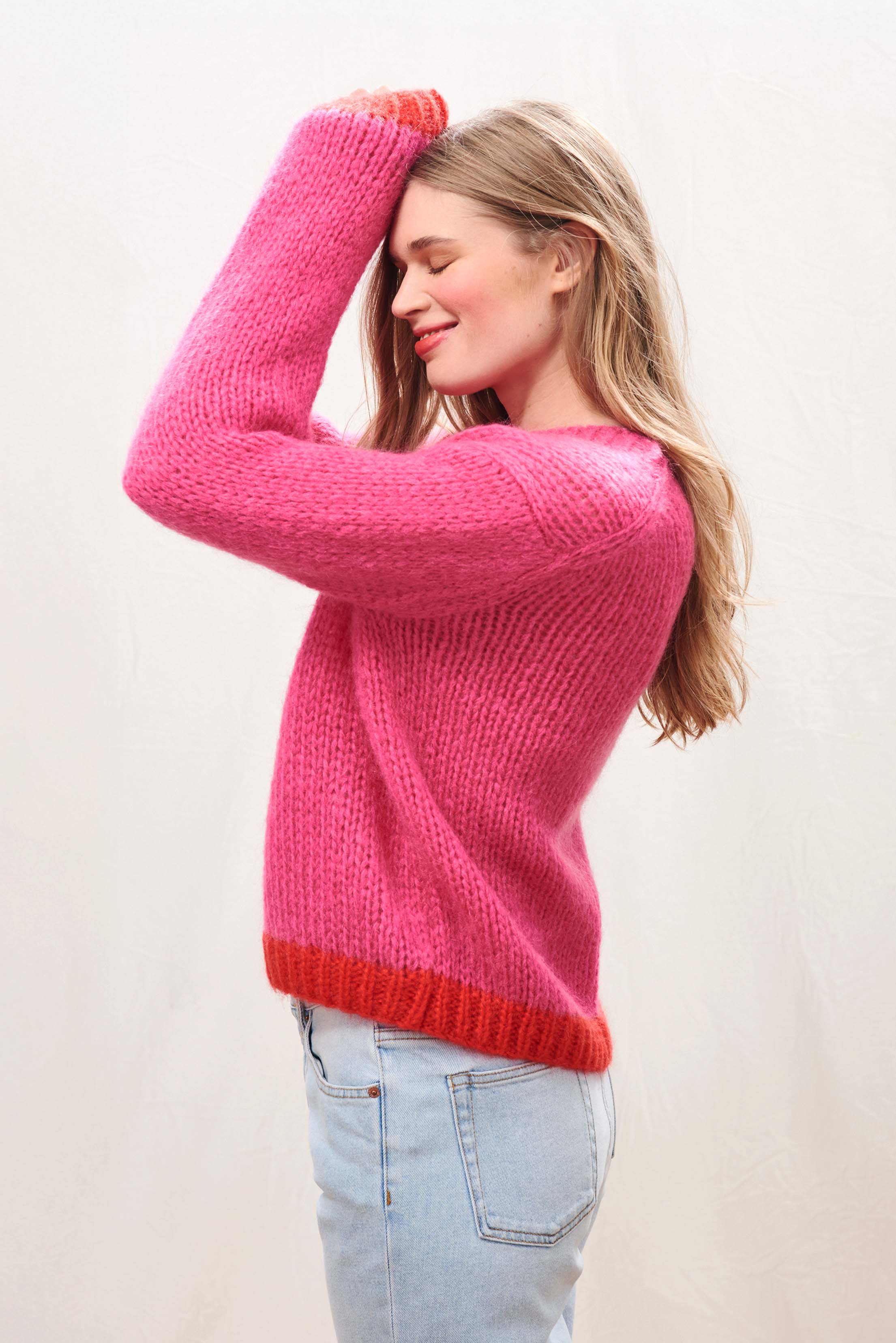 Female model wearing Jumper 1234 hand knitted mohair and wool blend hand knitted crew neck jumper in pink with red tipping.