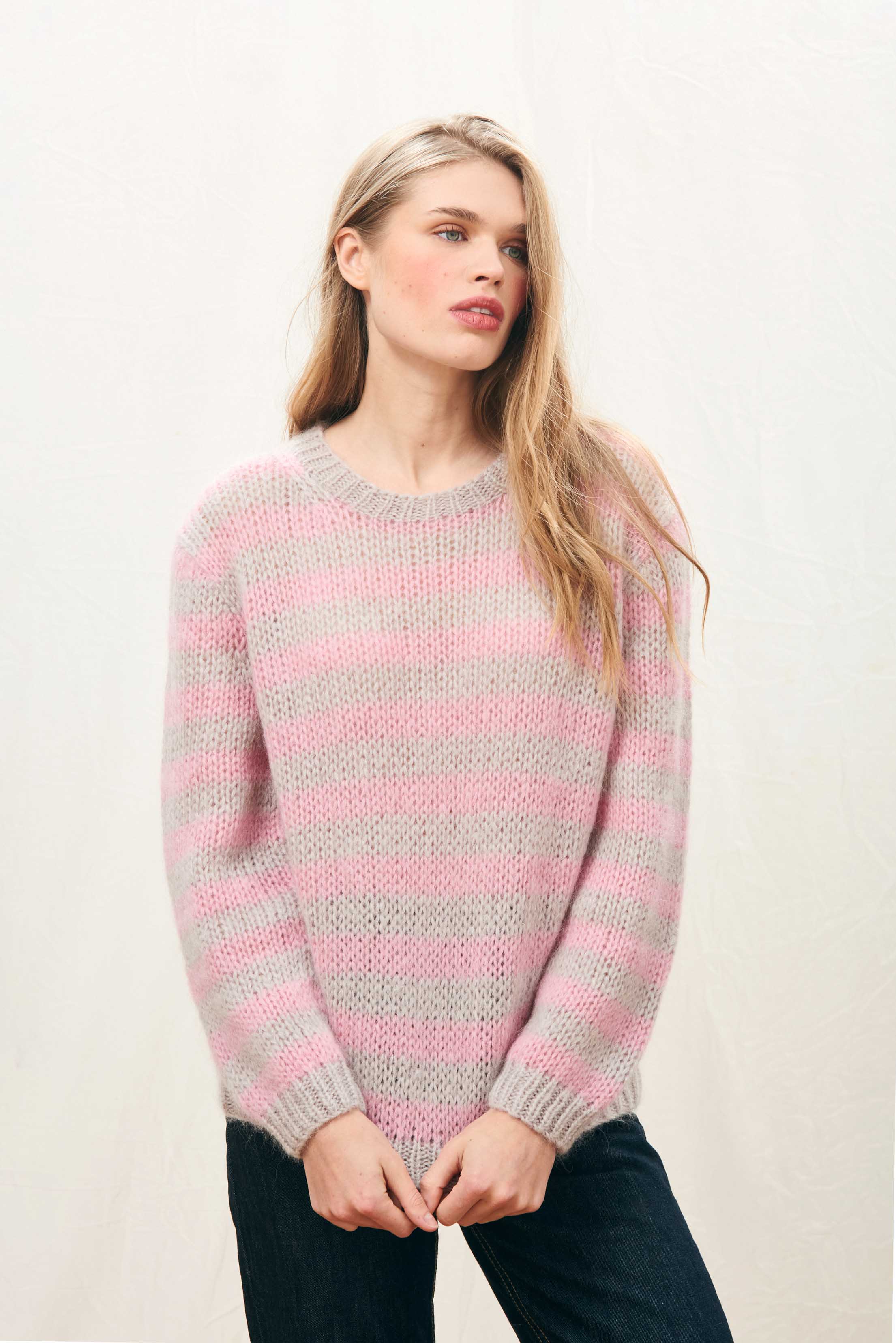 Female model wearing Jumper 1234 hand knitted mohair and wool blend hand knitted crew neck jumper in oyster and pink stripes.