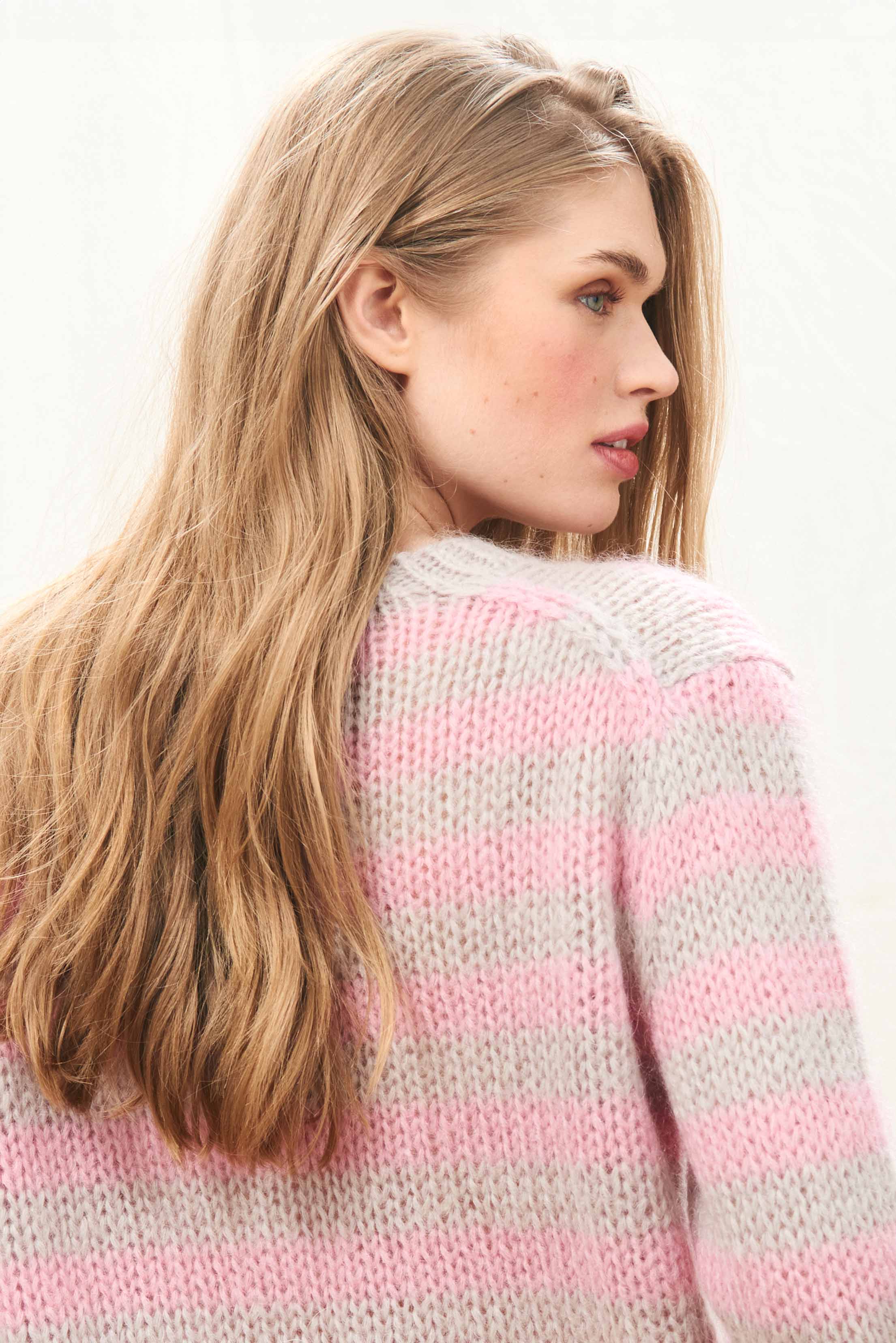 Female model wearing Jumper 1234 hand knitted mohair and wool blend hand knitted crew neck jumper in oyster and pink stripes.