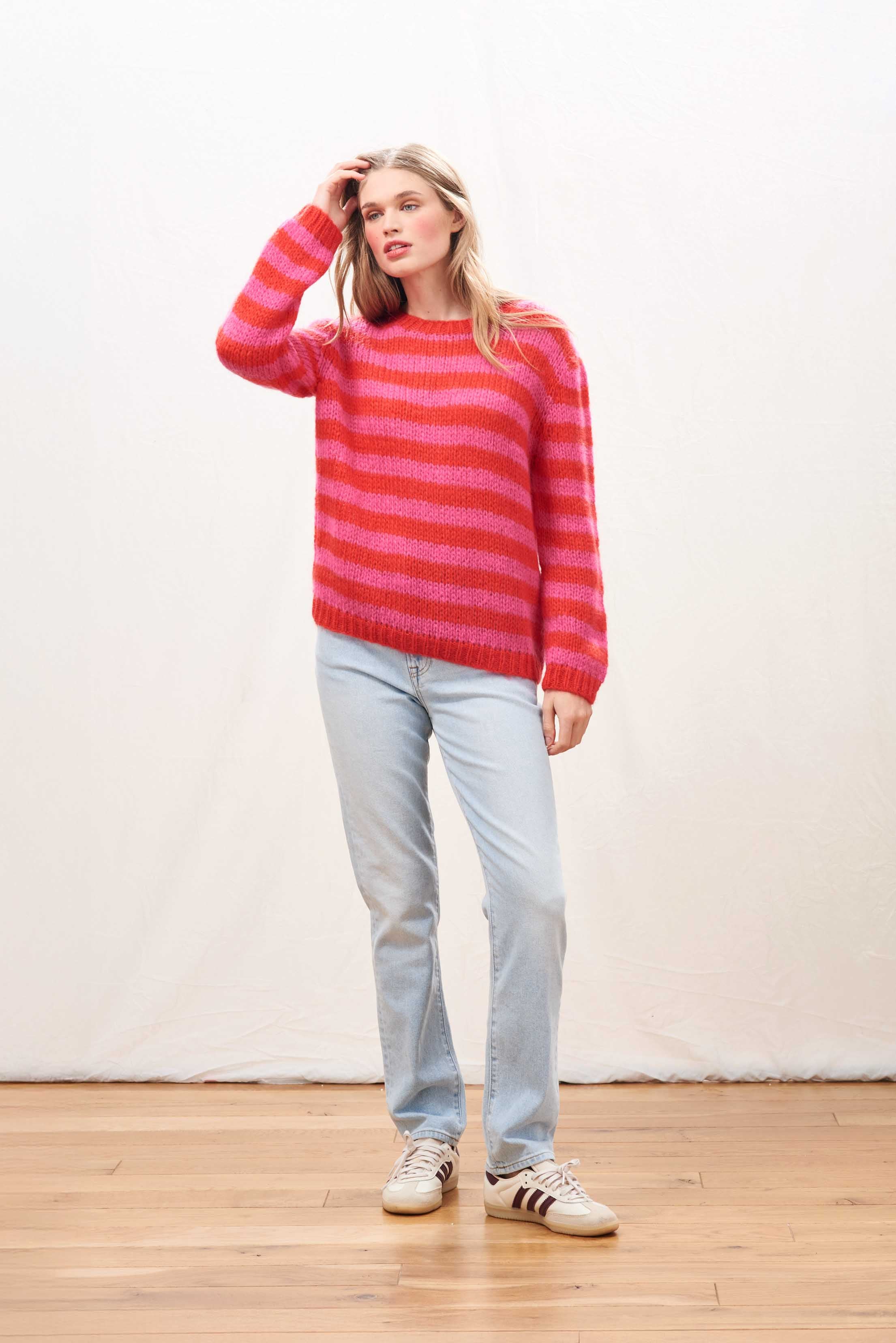Female model wearing Jumper 1234 hand knitted mohair and wool blend hand knitted crew neck jumper in pink and red stripes.