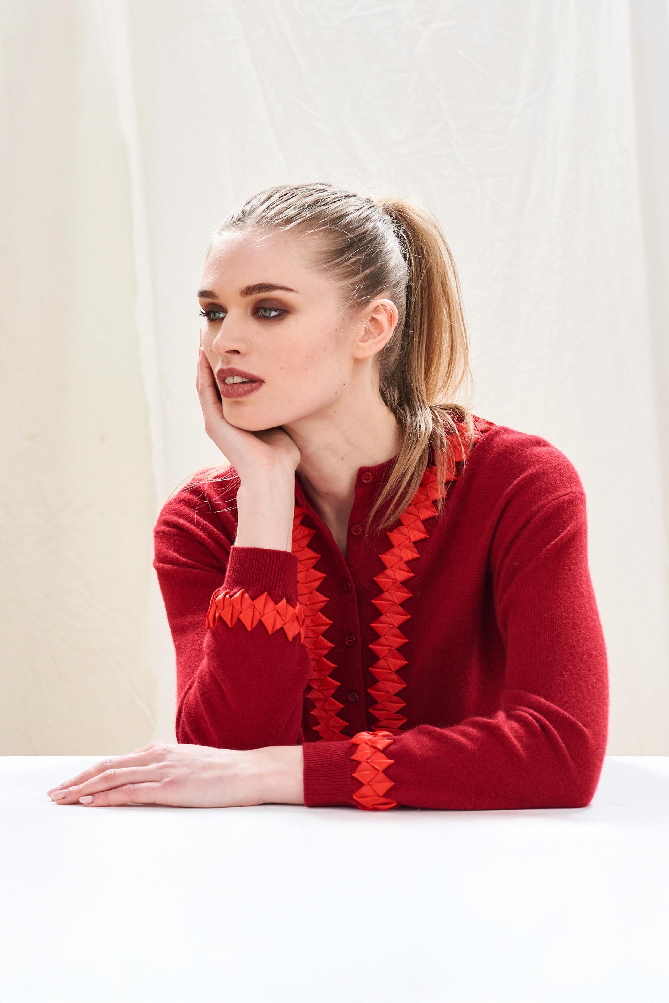 Female model wearing Jumper 1234 cashmere wool neat fit crew neck cardigan in burgundy with red twisted ribbon detail