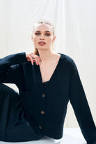 Female model wearing Jumper 1234 cashmere wool black oversize vee neck cardigan with Guernsey details, splits at the sides and it's slightly longer at the back