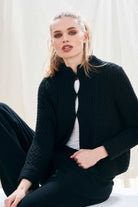 Female model wearing Jumper 1234 black heavy weight textured cardigan in cashmere wool, with hook and eye closure