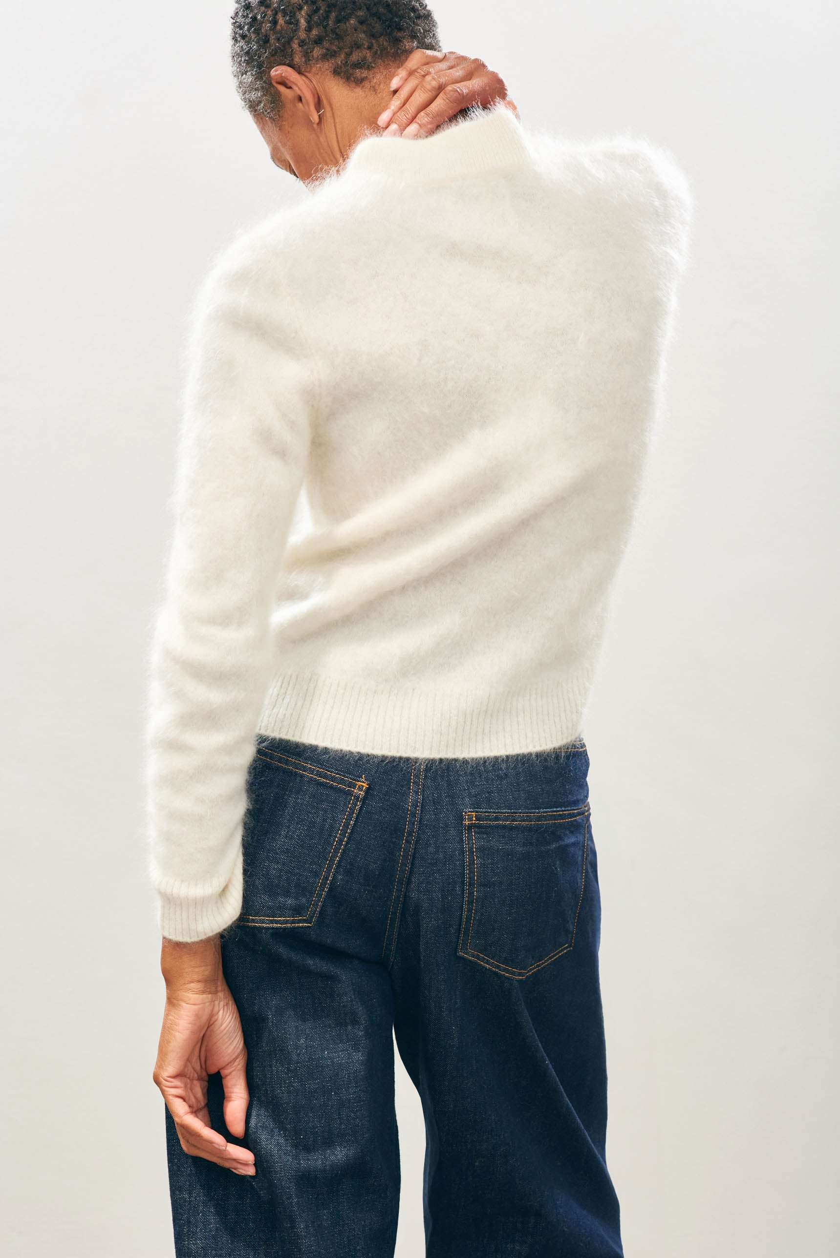 Female model wearing Jumper1234 Cashmere Brushed Turtle in Cream facing away from the camera