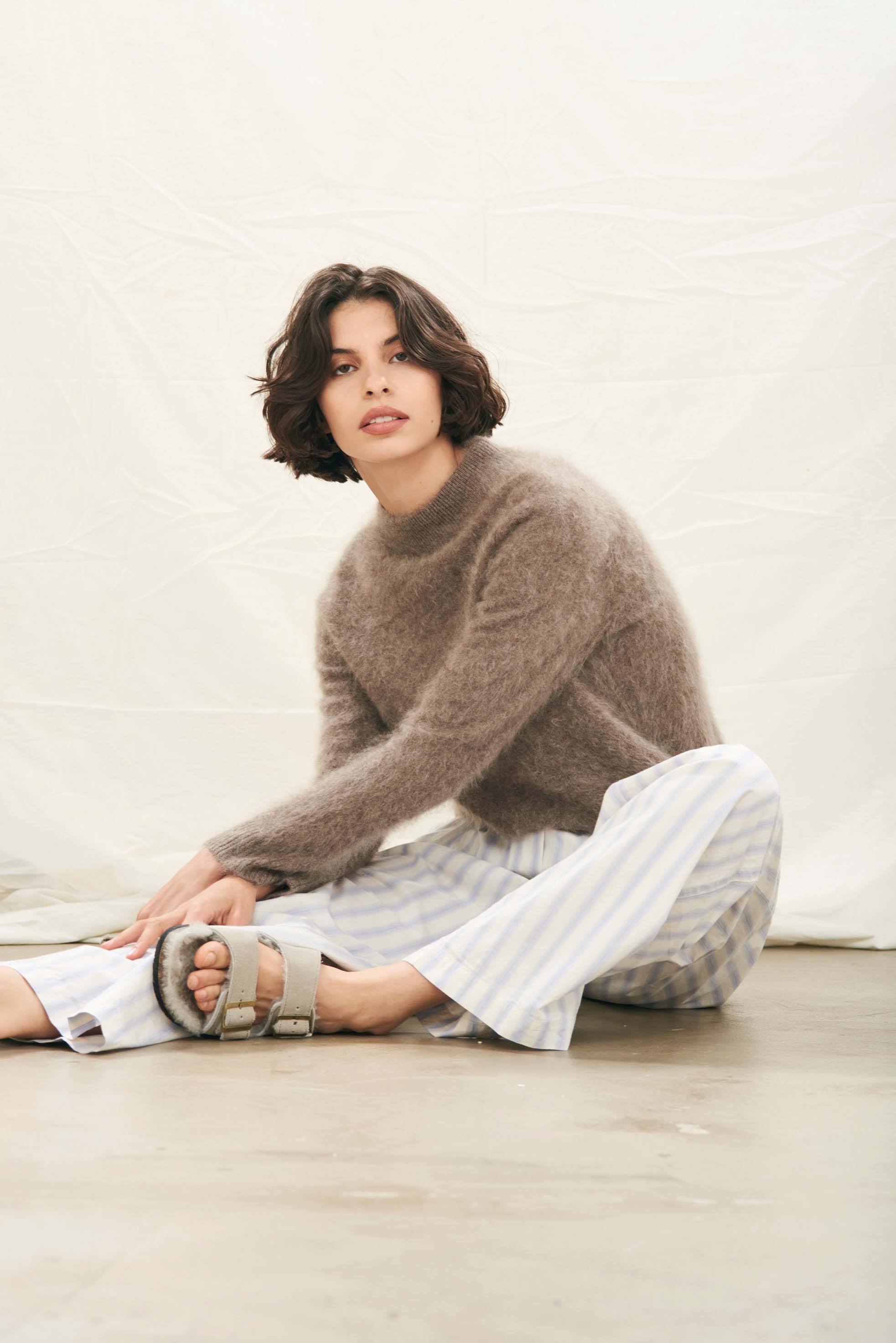 Female model wearing Jumper1234 Cashmere Brushed Turtle in Moose sitting on the floor
