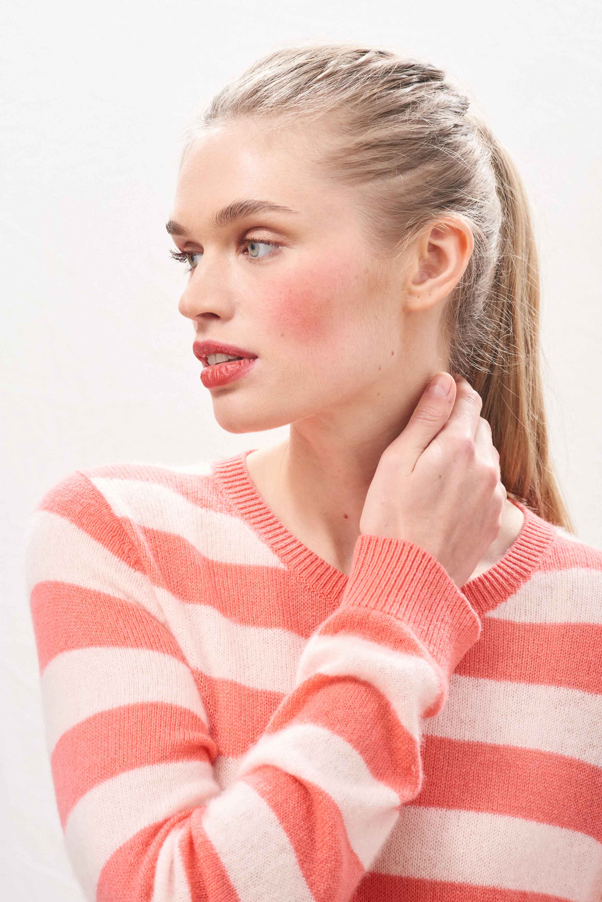 Female model wearing Jumper 1234 lightweight cashmere stripe crew neck in coral and pale pink.