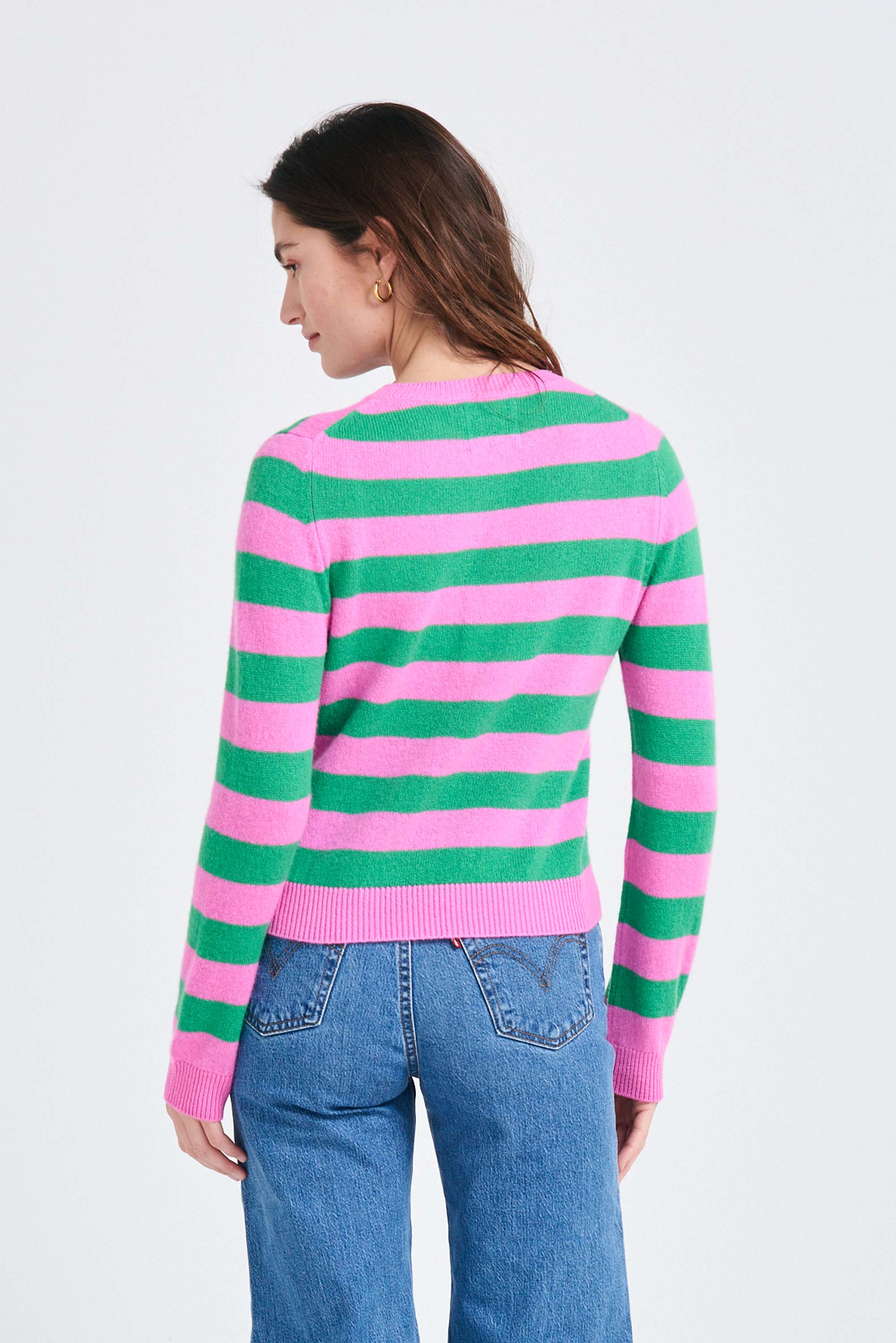 Brown haired female model wearing Jumper1234 Stripe cashmere crew neck jumper in peony and bright green facing away from the camera