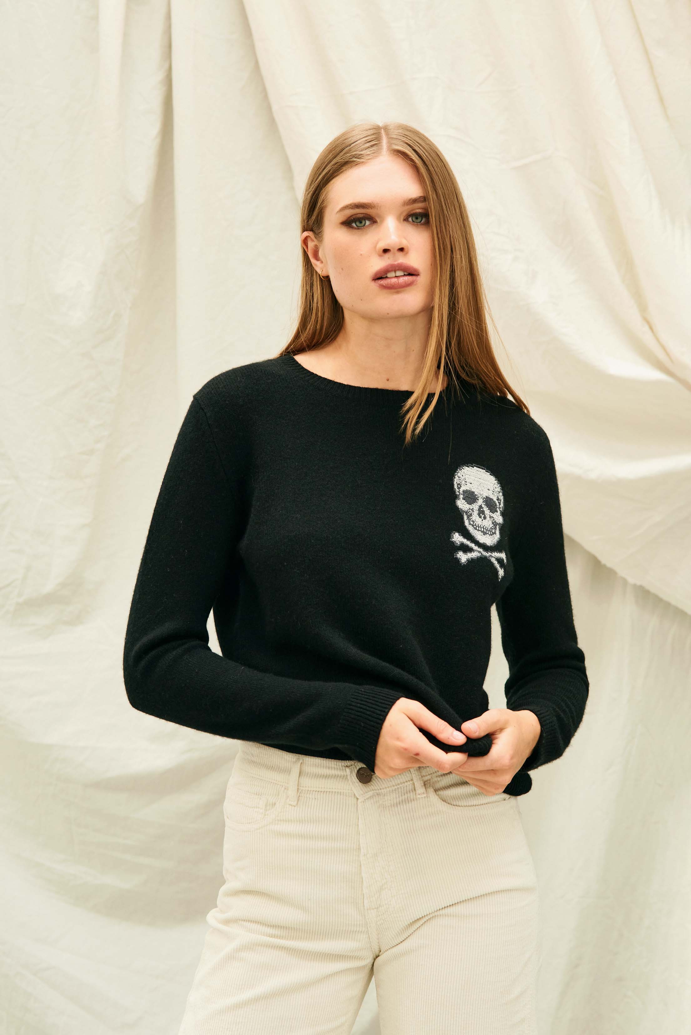 Female model wearing Jumper 1234 Black crew neck jumper in cashmere and wool, with an embroidered skull and crossbones on the chest.