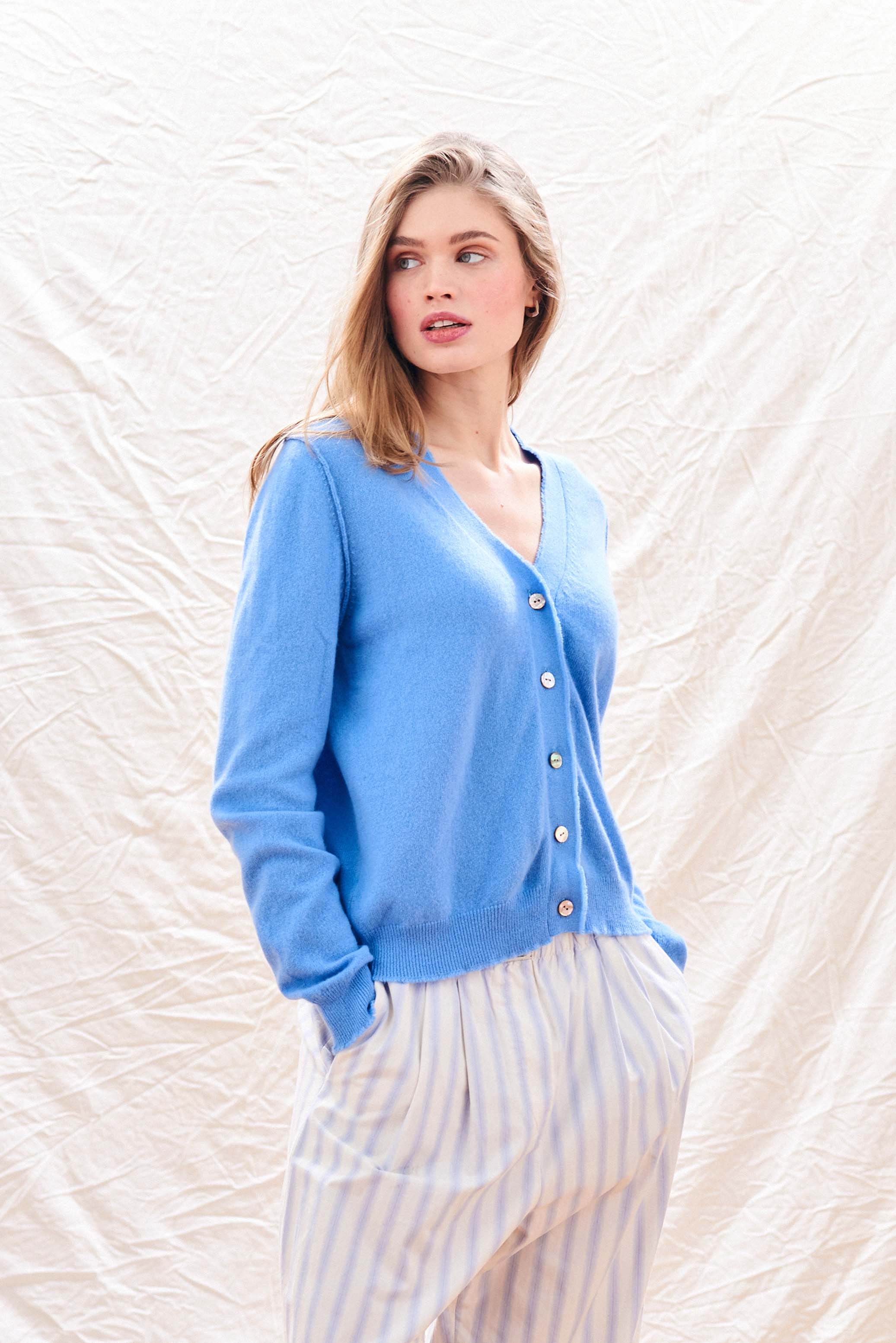 Blonde female model wearing Jumper 1234 Blue cashmere vee neck cardigan with 'distressed' ribs