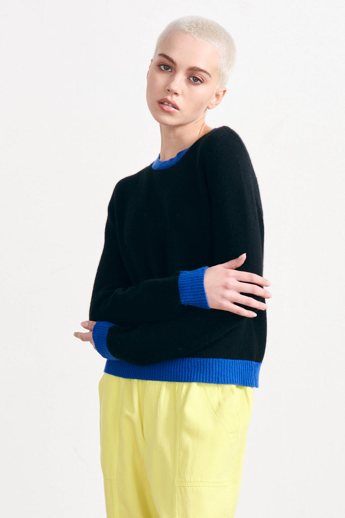 Blonde female model wearing Jumper 1234 black cashmere crew neck with contrast bright blue ribs