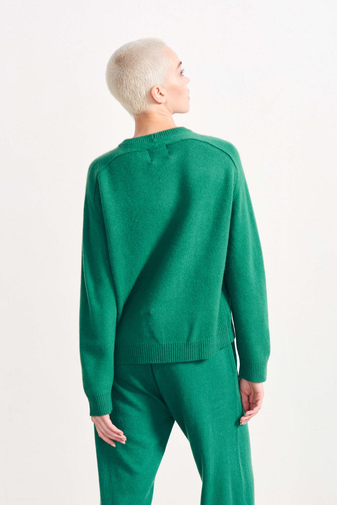 Blonde female model wearing Jumper1234 oversized cashmere crew in Grass Green facing away from the camera