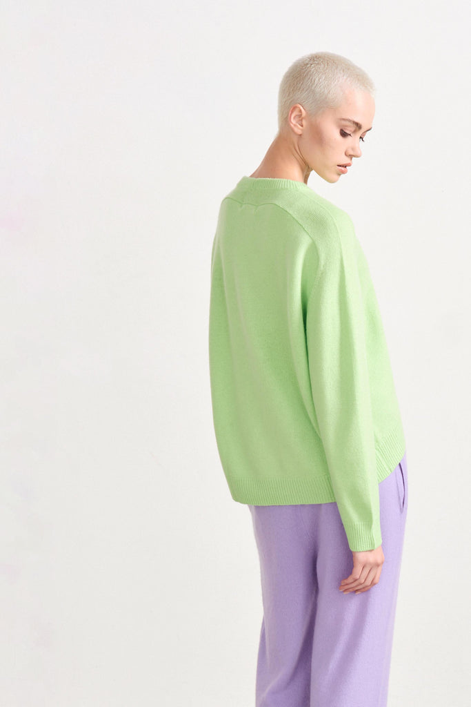 Blonde female model wearing Jumper1234 oversized cashmere crew in Lime Green facing away from the camera