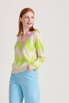 Red haired female model wearing Jumper1234 Oatmeal and acid green zig zag stripe cashmere jumper, with rose pink trim open collar