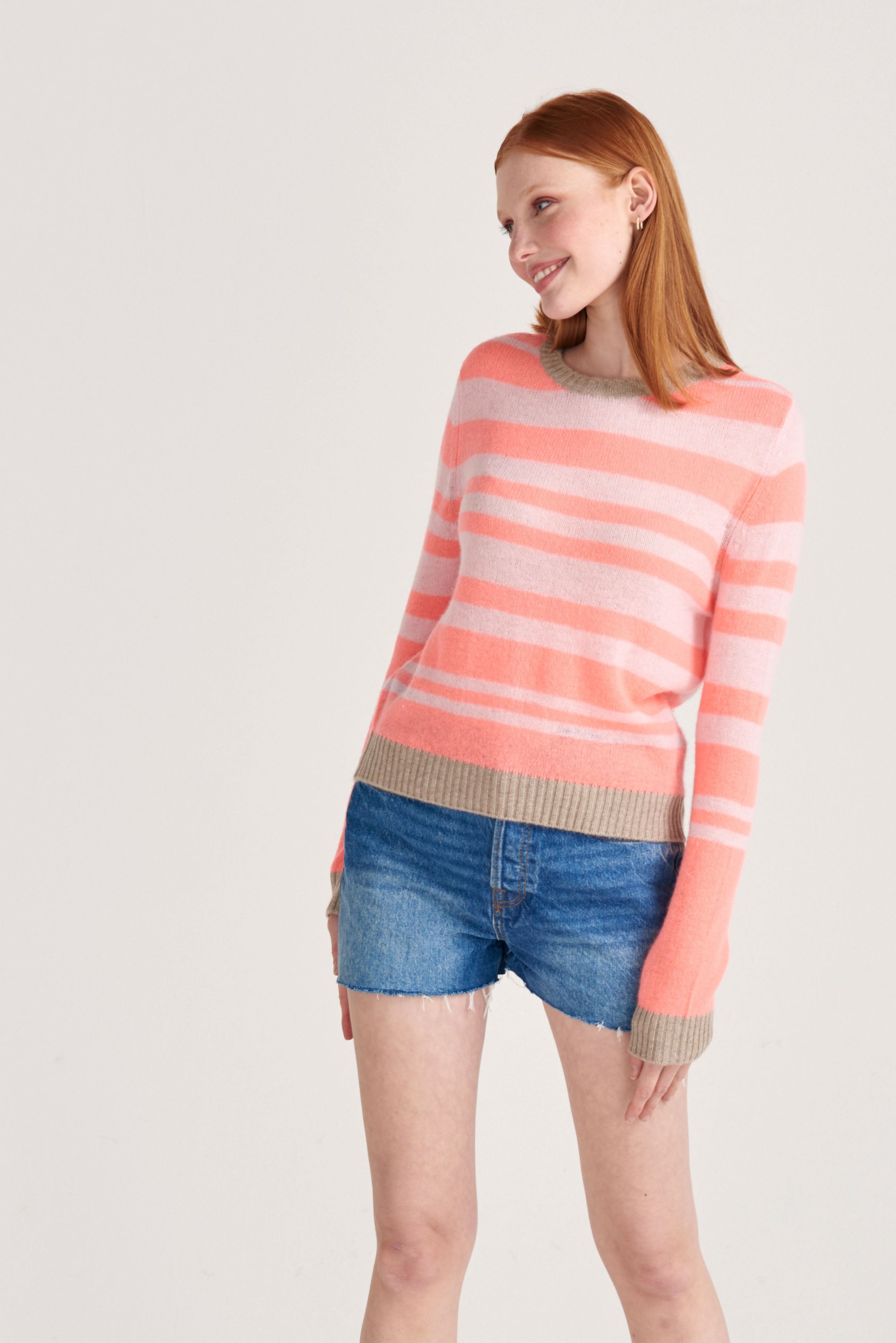 Red haired female model wearing Jumper1234 pale pink and neon coral stripe crew neck cashmere jumper with organic light brown contrast trims
