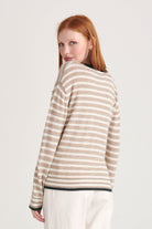 Red haired model wearing Jumper1234 Organic light brown and cream stripe vee neck cashmere jumper with contrast khaki ribs facing away from the camera