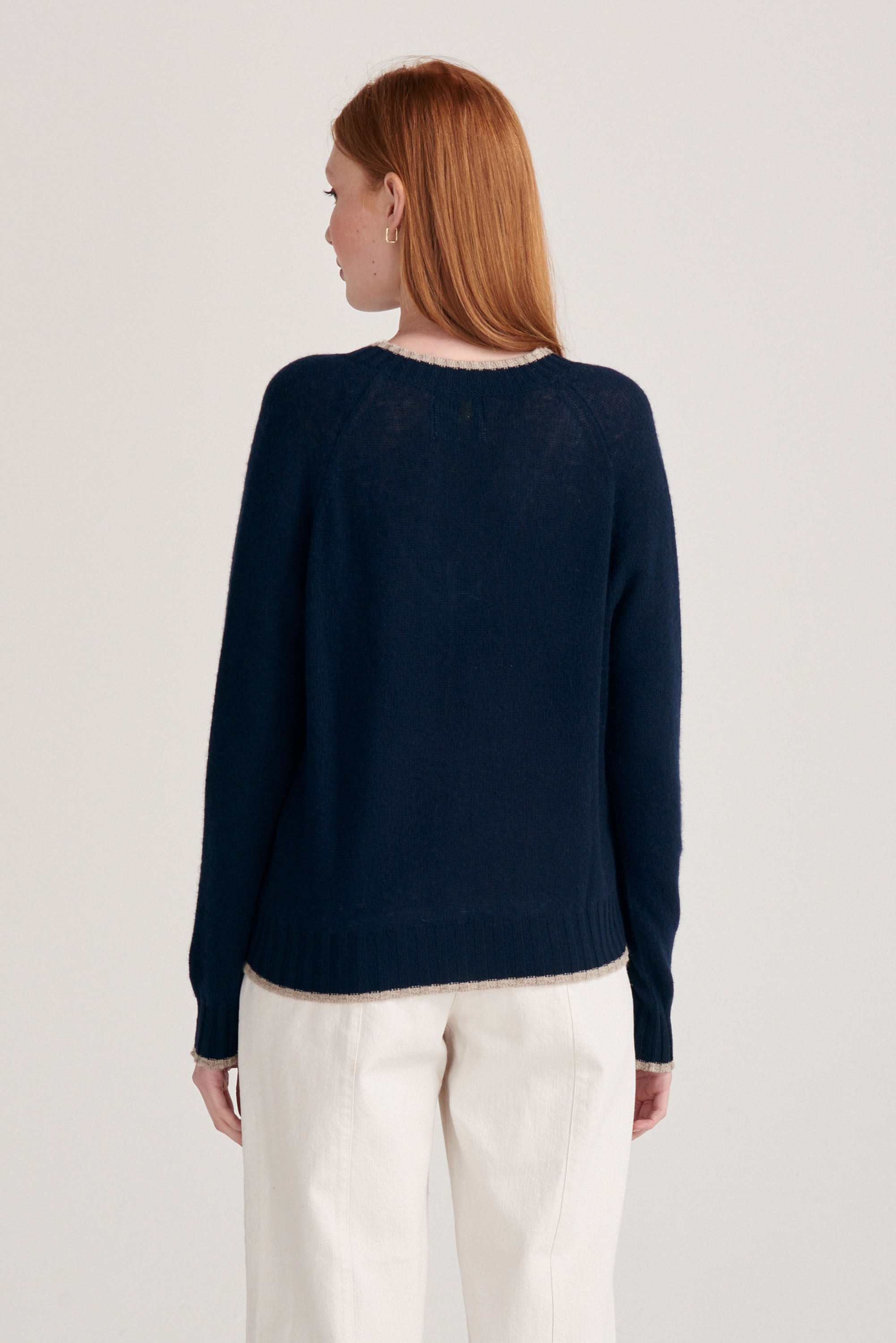 Red haired model wearing Jumper1234 cashmere vee neck jumper in navy with organic light brown tipping facing away from the camera