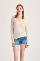 Red haired model wearing Jumper1234 cashmere vee neck jumper in oatmeal with acid green tipping