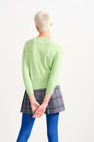 Blonde female model wearing Jumper 1234 Lime Green cashmere cardigan facing away from the camera