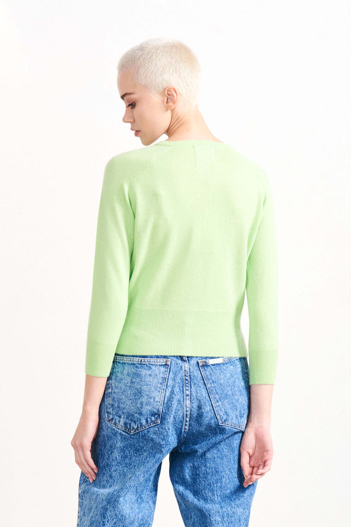 Blonde female model wearing Jumper 1234 Lime Green cashmere cardigan facing away from the camera