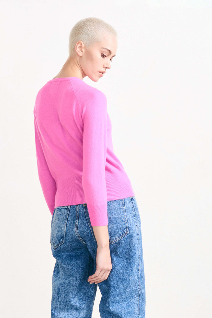 Blonde female model wearing Jumper 1234 Peony cashmere cardigan facing away from the camera