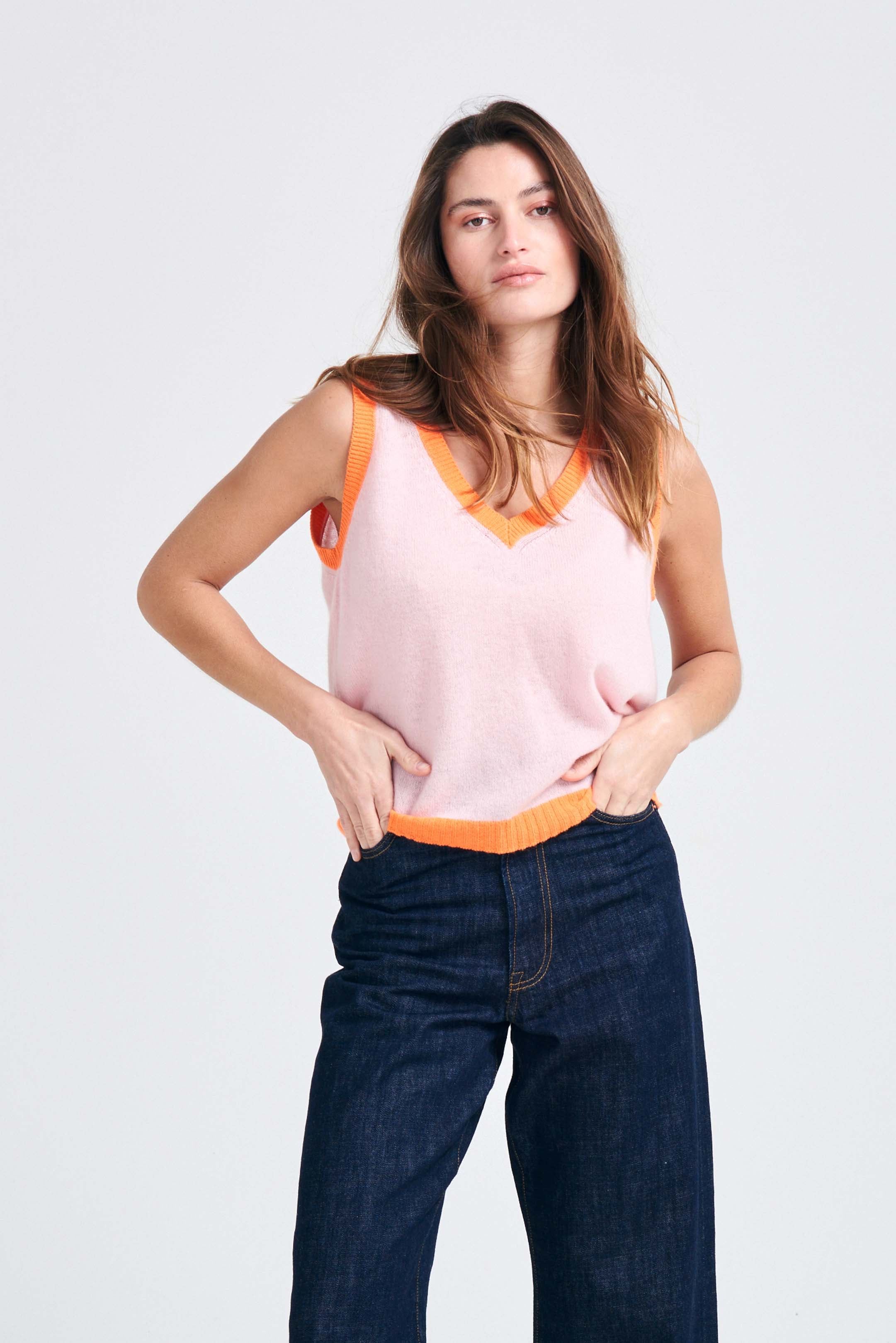 Brown haired female model wearing Jumper1234 Pale pink cashmere vee neck tank with contrast neon orange ribs