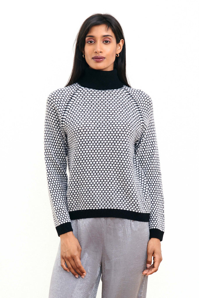 Brown haired female model wearing Jumper1234 "honeycomb" cashmere roll neck in black and pale grey circular contrast knit