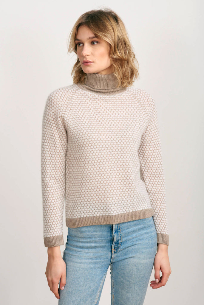 Blonde female model wearing Jumper1234 "honeycomb" cashmere roll neck in organic light brown and cream circular contrast knit