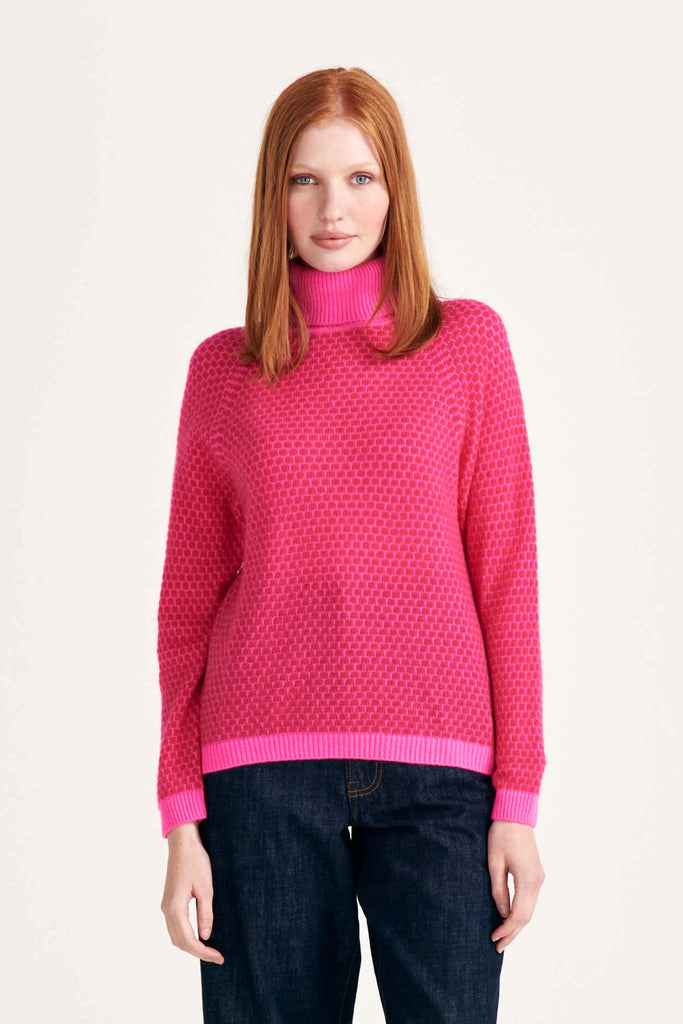 Ginger female model wearing Jumper1234 "honeycomb" cashmere roll neck in hot pink and cherry circular contrast knit