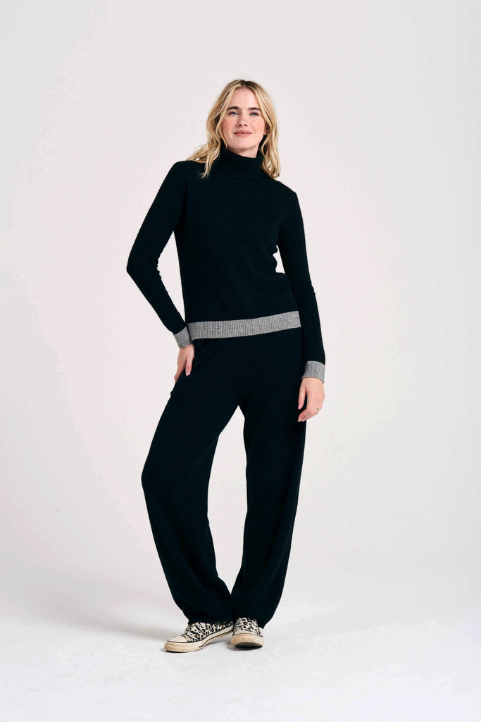 Blonde female model wearing Jumper1234 black cashmere roll collar with contrasting mid grey ribs