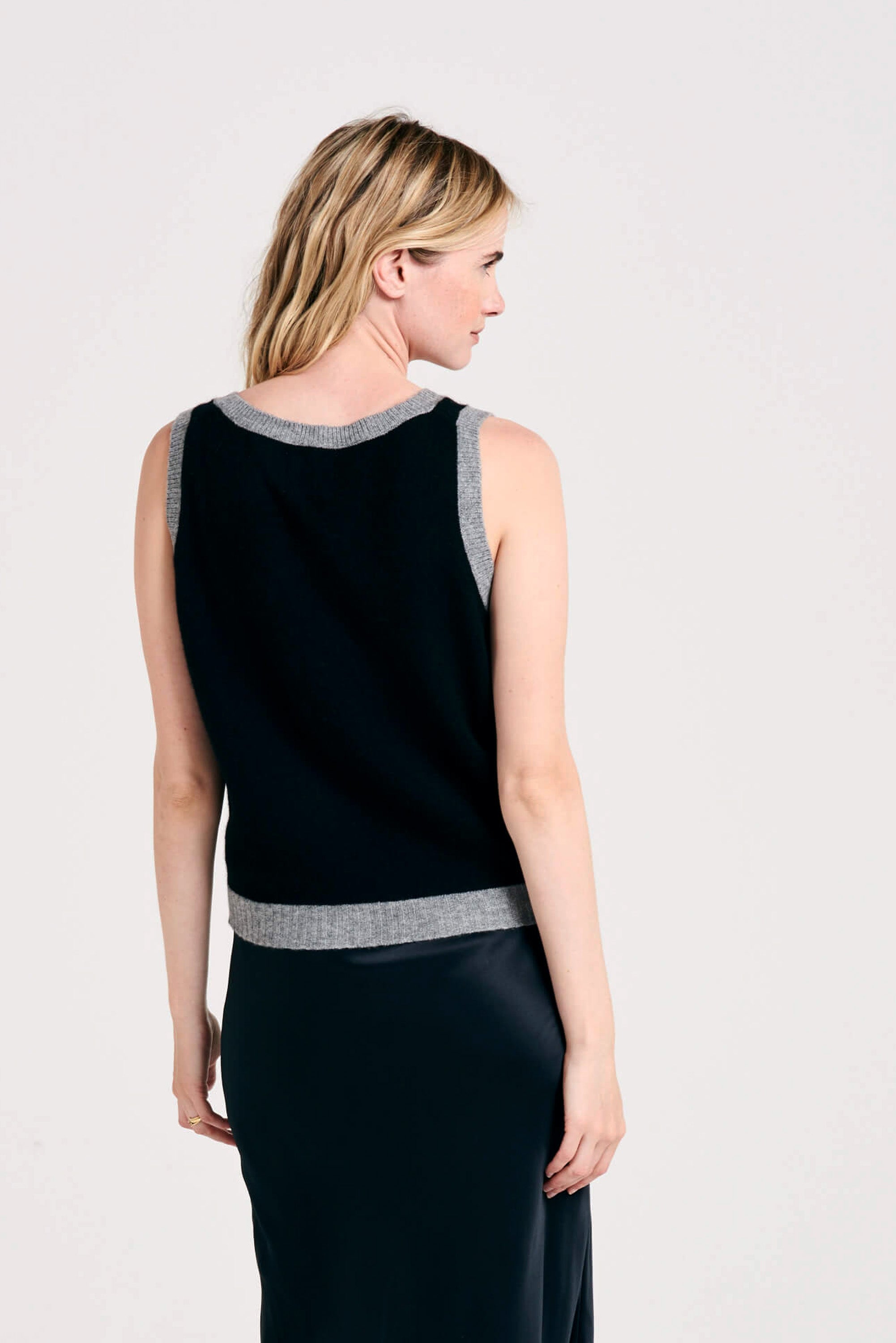 Blonde female model wearing Jumper1234 contrast cashmere tank in black and mid grey facing away from the camera