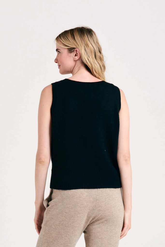 Blonde female model wearing Jumper1234 lightweight cashmere tank in black facing away from the camera
