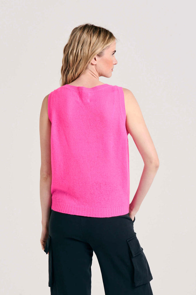 Blonde female model wearing Jumper1234 lightweight cashmere tank in hot pink facing away from the camera