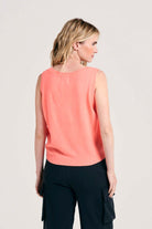Blonde female model wearing Jumper1234 lightweight cashmere tank in neon coral facing away from the camera