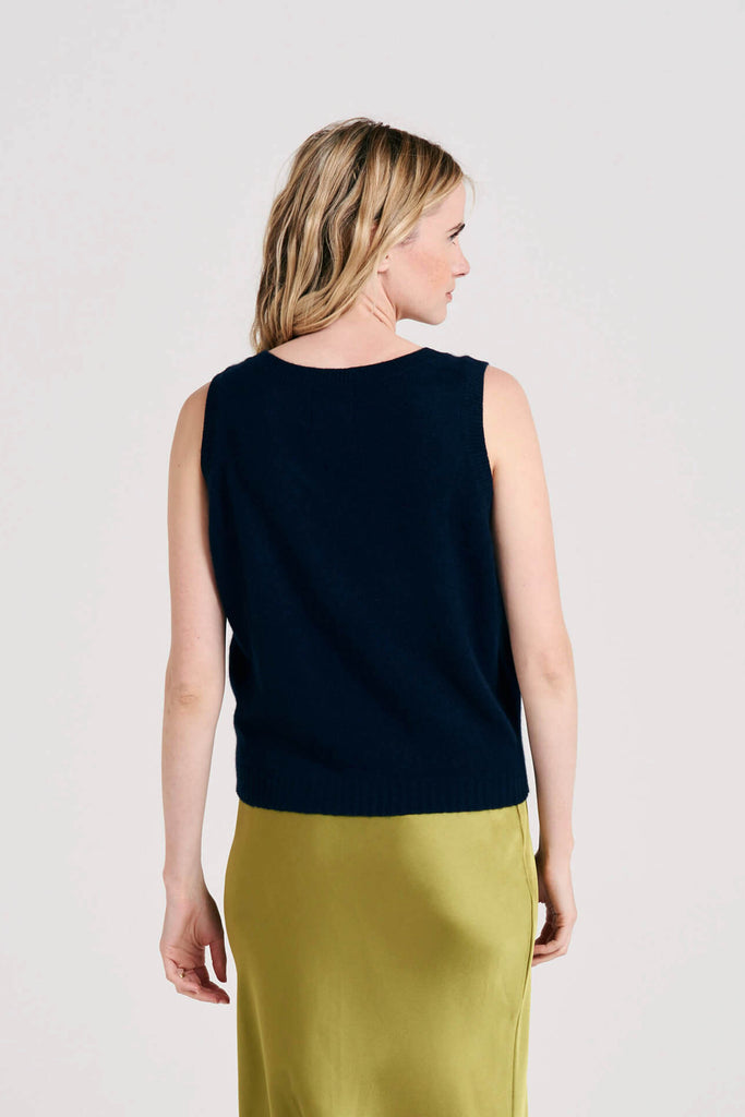 Blonde female model wearing Jumper1234 lightweight cashmere tank in navy facing away from the camera