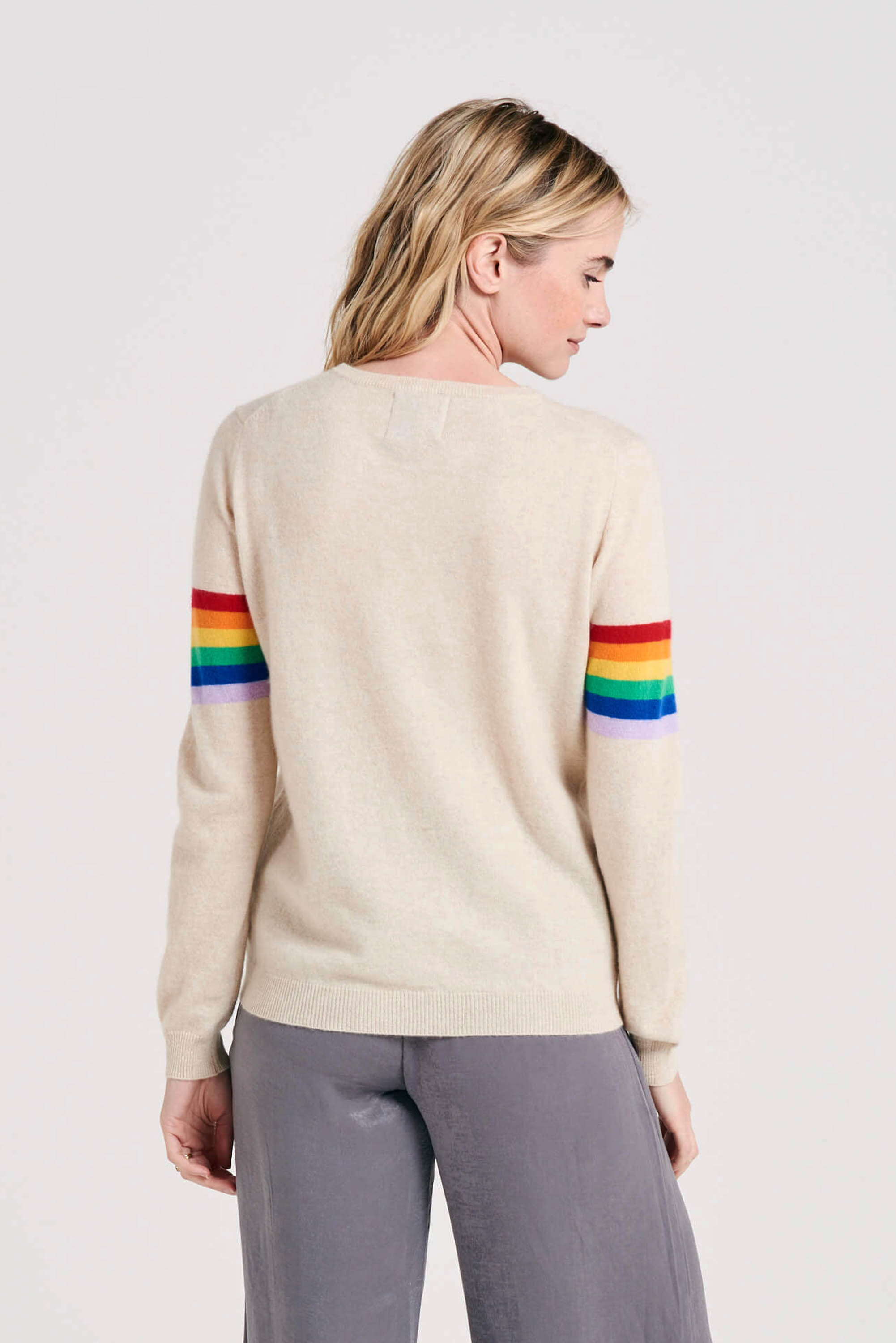 Blonde female model wearing Jumper1234 Rainbow arms cashmere crew in oatmeal facing away from the camera