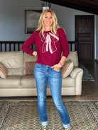 Gayle Rinkoff wearing Jumper1234 Burgundy classic fit crew neck jumper with folklore-inspired intarsia bow in pink and cream