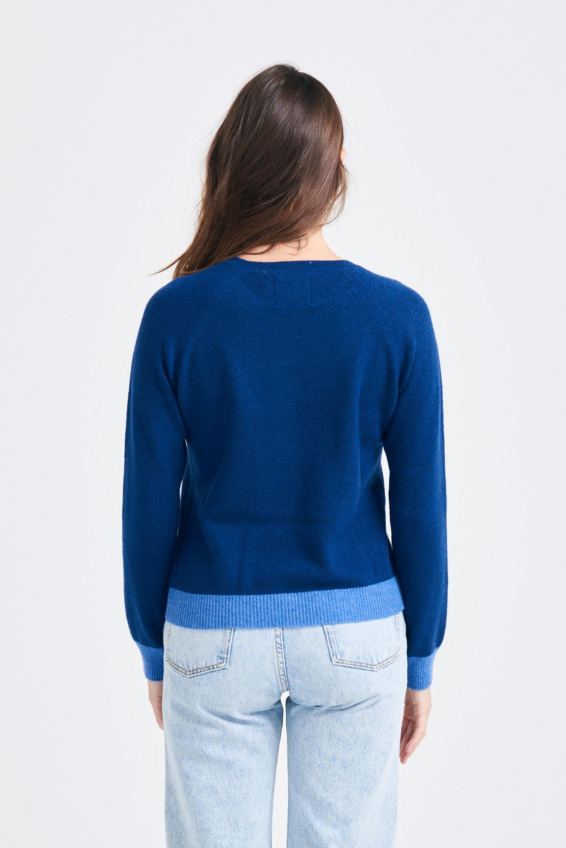 Brown haired female model wearing Jumper1234 denim cashmere crew neck jumper with periwinkle contrast ribs facing away from camera