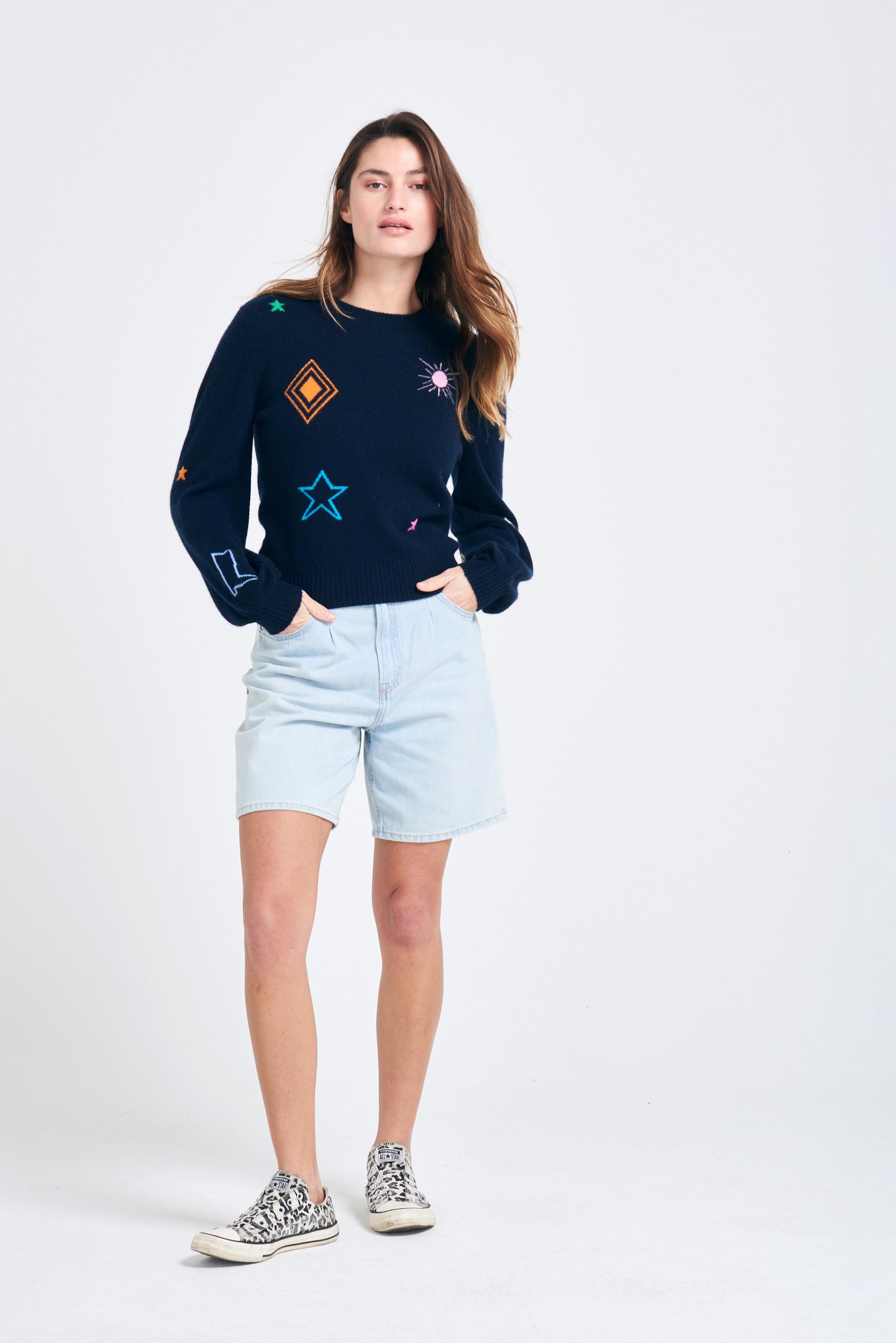 Brown haired female model wearing Jumper1234 Navy cashmere jumper with multi coloured cowboy icons back and front with slightly puff sleeves