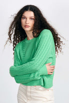 Brown haired female model wearing Jumper1234 Apple green cotton aran crew neck jumper with a ribbon tie back