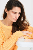 Brown haired female model wearing Jumper1234 Apricot cotton aran crew neck jumper with a ribbon tie back