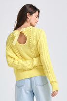 Brown haired female model wearing Jumper1234 Yellow cotton aran crew neck jumper with a ribbon tie back, back shot facing away from the camera