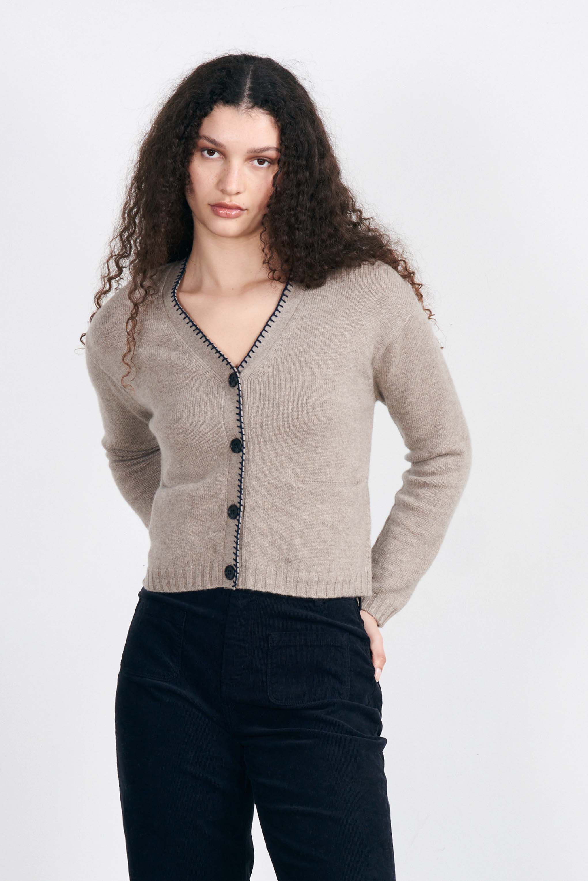 Model wearing Jumper1234 Cashmere vee neck cardigan in organic light brown with contrast navy blanket stitch detail