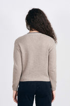 Model facing away from the camera wearing Jumper1234 Cashmere vee neck cardigan in organic light brown with contrast navy blanket stitch detail