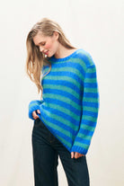 Female model wearing Jumper 1234 hand knitted mohair and wool blend hand knitted crew neck jumper in blue and green stripes.