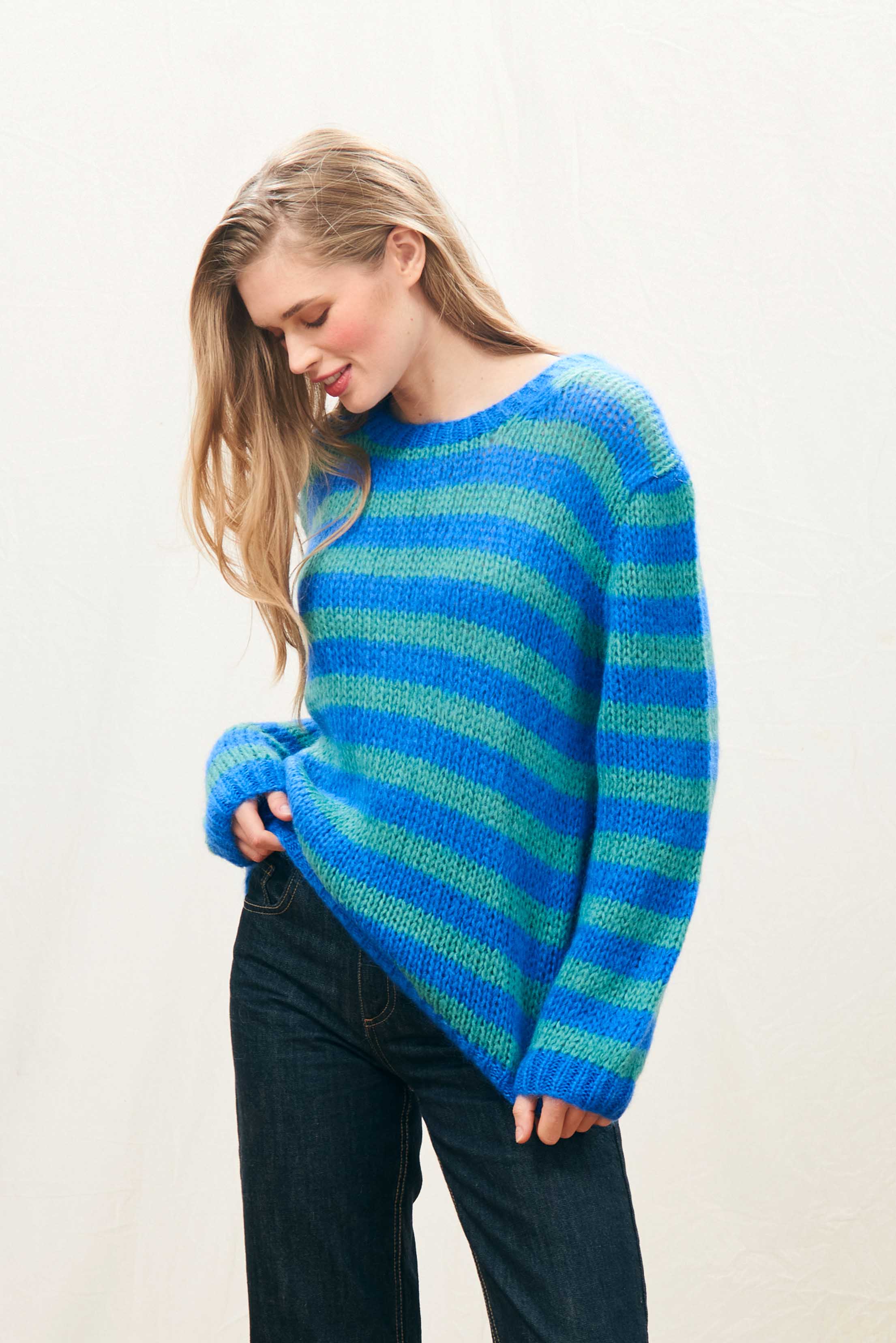 Female model wearing Jumper 1234 hand knitted mohair and wool blend hand knitted crew neck jumper in blue and green stripes.