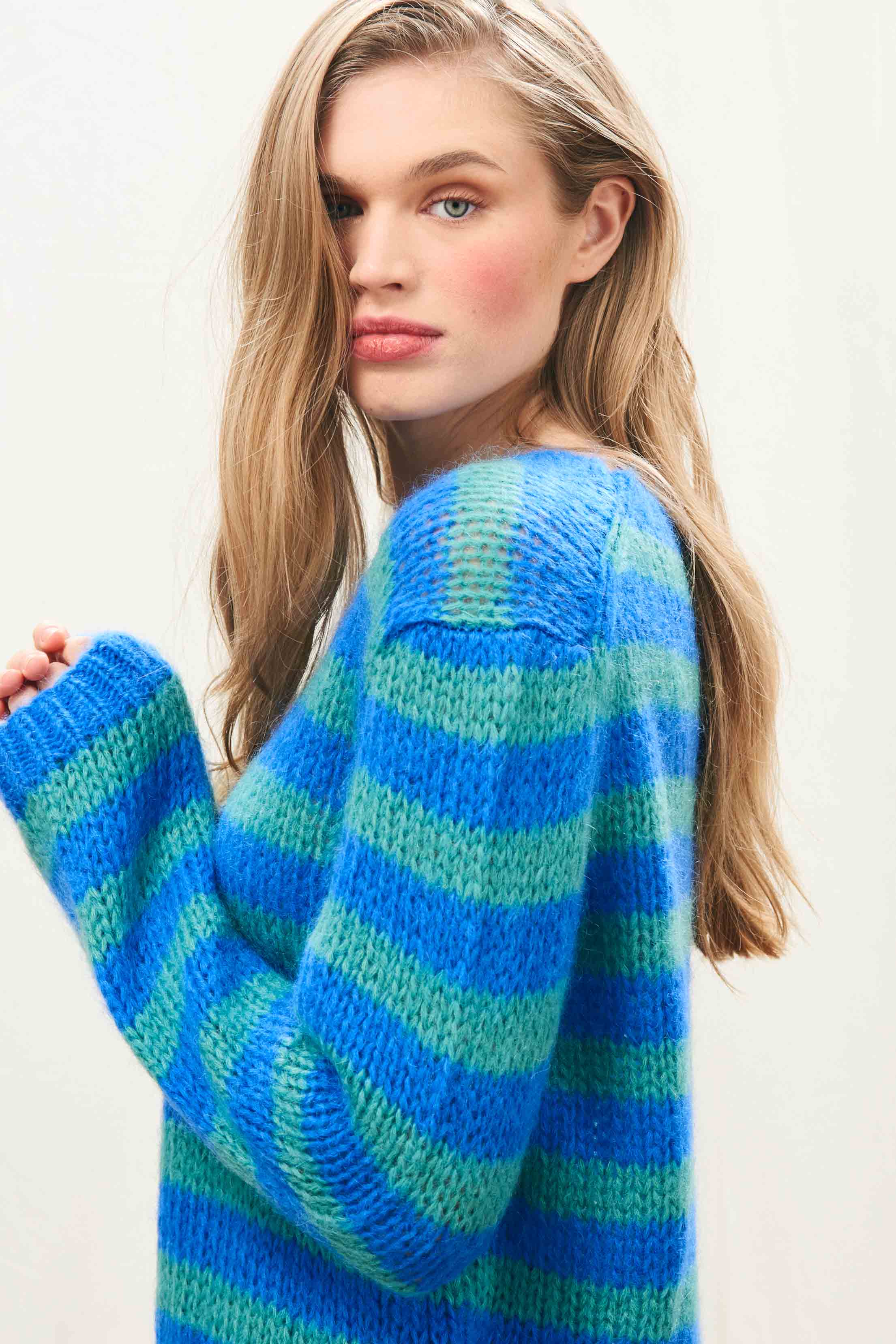 Female model wearing Jumper 1234 hand knitted mohair and wool blend hand knitted crew neck jumper in blue and green stripes.