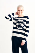 Blonde female model wearing Jumper1234 Navy and cream stripe cashmere crew neck jumper with miss matched stripe love intarsia