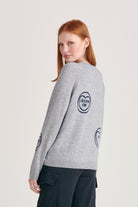 Red haired female model wearing Jumper1234 mid grey cashmere and wool mix crew neck sweatshirt style jumper with all over navy love hearts intarsia facing away from the camera